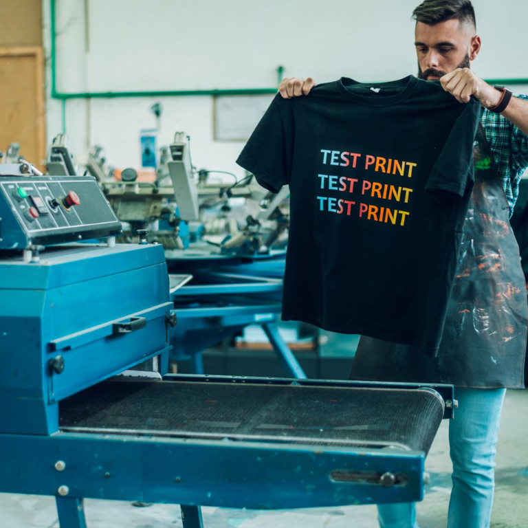 Screen printing test print displayed on a black t-shirt in a print shop
